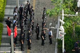 A Chinese police officer instructs security guards on duty around Evergrande headquarters in Shenzhen, southern China.