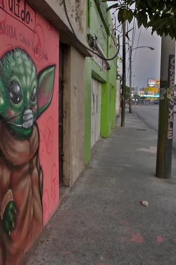 Un graffiti del personaje de Star Wars, Baby Yoda, con una máscara facial, está pintado en una pared en la ciudad de Guatemala