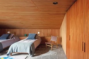 Al lado de las camas, sillón ‘Tanet’ con correas de cuero tejido (Landmark)