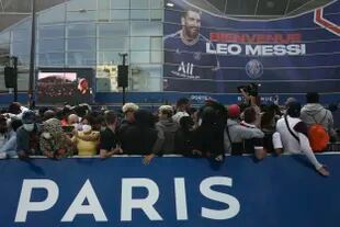 Paris Saint-Germain supporters gather outside the Parc des Princes stadium before Lionel Messi's press conference Wednesday, Aug. 11, 2021 in Paris. Lionel Messi finally signed his eagerly anticipated Paris Saint-Germain contract on Tuesday night to complete the move that confirms the end of a career-long association with Barcelona and sends PSG into a new era. (AP Photo/Rafael Yaghobzadeh)