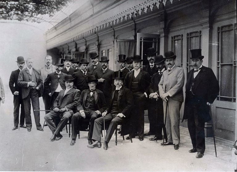 Visita de Bartolomé Mitre (sentado en el centro) al MHN. Adolfo P. Carranza es el segundo de pie, desde la izquierda, delante del señor de bombín. 1901.