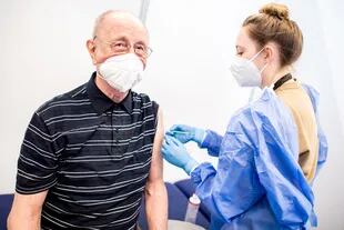 Heinrich Atoni recibe una dosis de la vacuna de Pfizer-BioNTech en el centro de vacunación instalado en el recinto ferial de Bremen, noroeste de Alemania