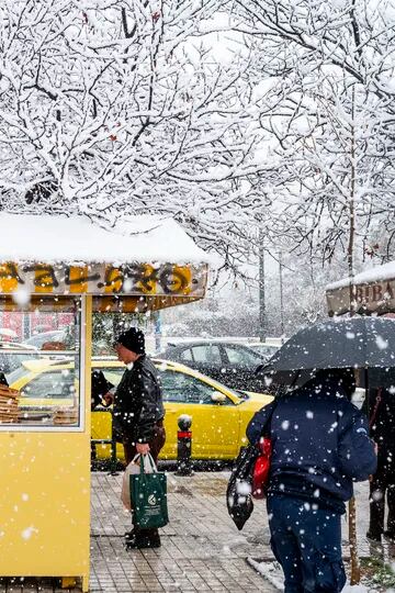Un hombre compra pan en un pequeño puesto durante la nevada en Atenas, Grecia
