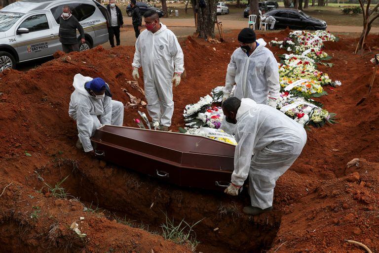 Sepultureros con trajes protectores se preparan para enterrar el ataúd que contiene el cuerpo de Elisa Moreira de Araujo, de 79 años, sospechoso de haber muerto por la enfermedad del coronavirus, en el cementerio de Vila Formosa, en Sao Paulo, Brasil.