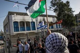 Árabes ondean banderas palestinas contra los israelíes en un edificio de la comunidad judía durante los nuevos disturbios en la ciudad de Lod.
