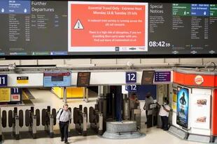 Commuters walk under a message board warning of severe heat disturbances at Victoria Station in London on July 18, 2022.