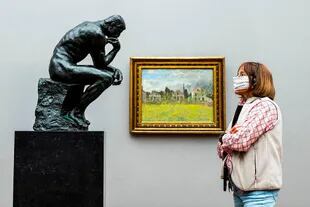 Una visitante con barbijo mira la escultura icónica de Auguste Rodin "El pensador" en la Old National Gallery en Berlín