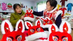 Mujeres confeccionan sombreros de conejo para la celebración del Año Nuevo chino.
