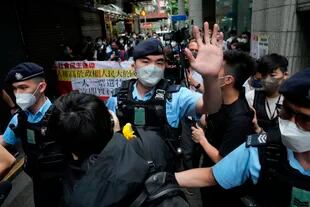 Manifestantes a favor de la democracia son rodeados por agentes de policía mientras llevan una pancarta contra la elección del jefe del ejecutivo cerca de un colegio electoral en Hong Kong, el domingo 8 de mayo de 2022.