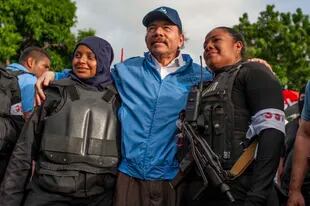 Nicaraguan police officers take a photo with President Daniel Ortega, in Masaya, Nicaragua, on Friday, July 13, 2018. (AP Photo/Cristobal Venegas, File)