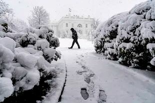 Una persona camina en medio de una nevada frente a la Casa Blanca, el lunes 3 de enero de 2022, en Washington. (AP Foto/Andrew Harnik)