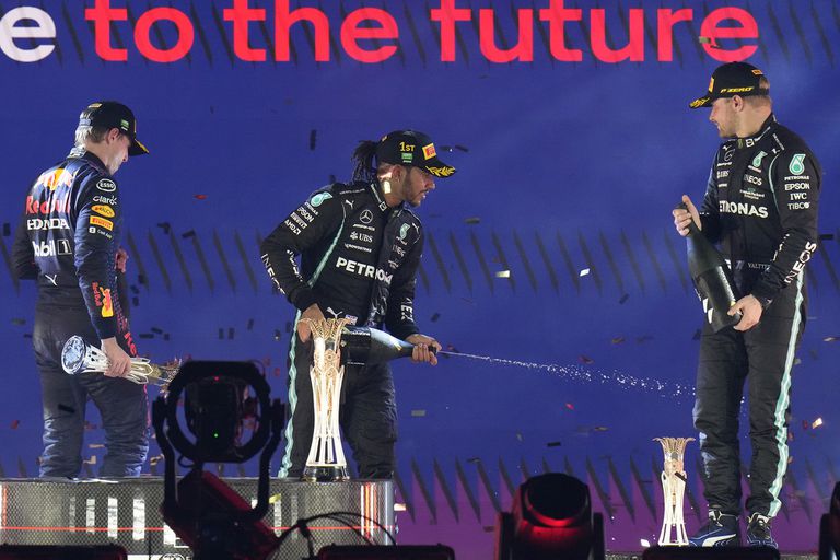 Mientras Lewis Hamilton comienza con el ritual de celebración por la victoria con su compañero Valtteri Bottas, Max Verstappen abandona el podio de Jeddah; Mercedes aventaja por 28 puntos a Red Bull Racing en el Mundial de Constructores