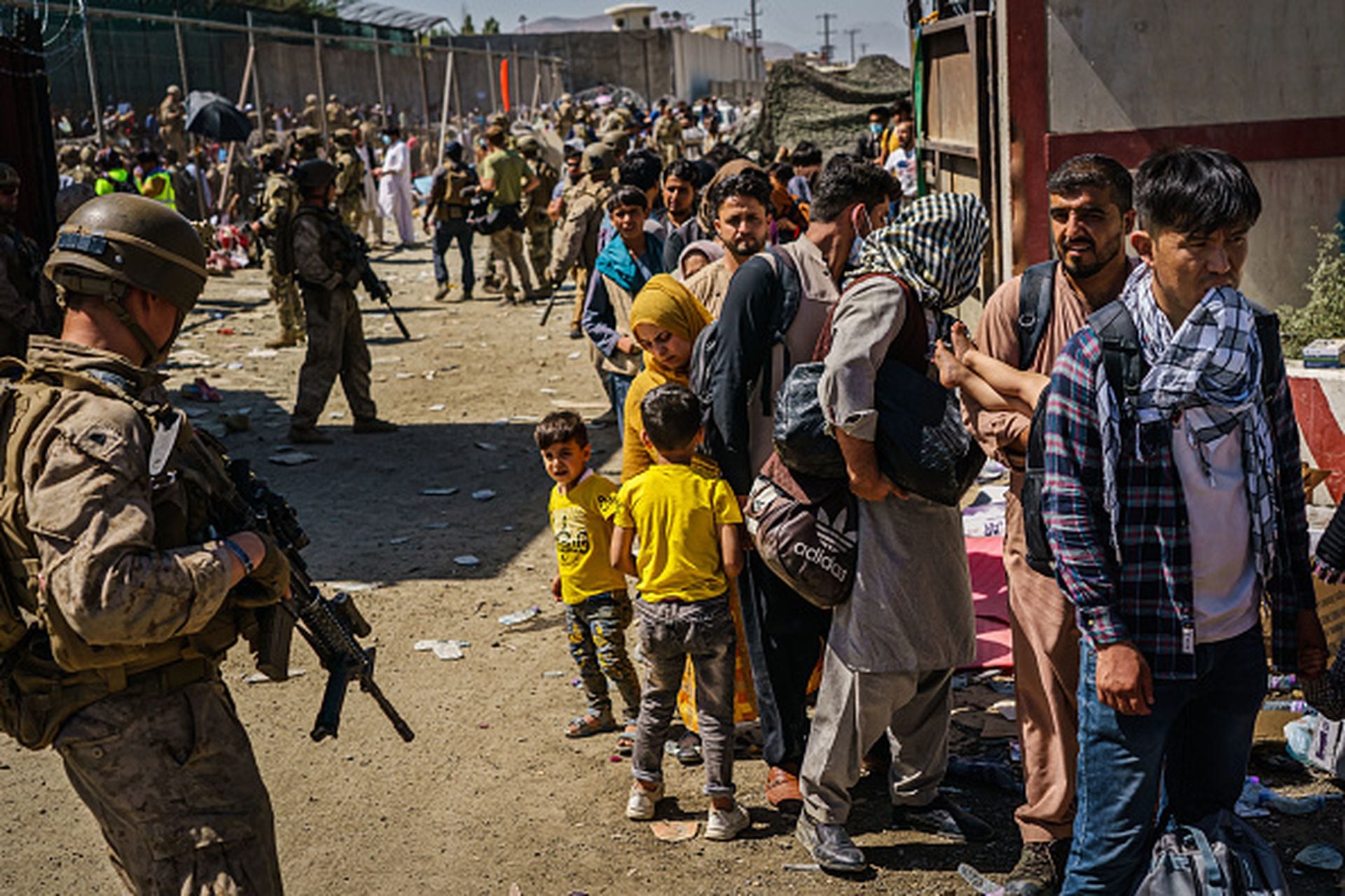 Soldados estadounidenses vigilan a los refugiados afganos que esperan en la fila para ser enlistados para un vuelo de salida de Kabul, Afganistán