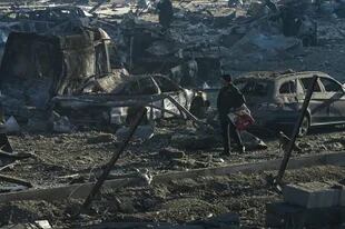 Un hombre pasea a su perro junto a vehículos quemados y escombros tras el ataque con misiles contra el centro comercial Retroville en Kiev el 21 de marzo de 2022.