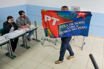 Un votante muestra una bandera del Partido de los Trabajadores del expresidente brasileño Luiz Inácio Lula da Silva, quien vuelve a postularse para presidente, antes de votar en las elecciones generales en Sao Paulo, Brasil, el domingo 2 de octubre de 2022