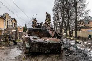Soldados ucranianos intentan recuperar piezas de un vehículo blindado ruso en Bucha, Ucrania, el domingo 3 de abril de 2022