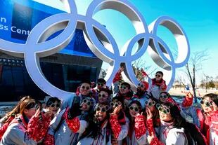 Los voluntarios olímpicos de Pyeongchang posan para una foto junto a los anillos olímpicos