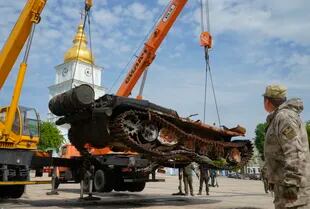 Soldados ucranianos descargan un tanque ruso destruido para instalarlo como símbolo de guerra en el centro de Kiev, Ucrania, el viernes 20 de mayo de 2022.