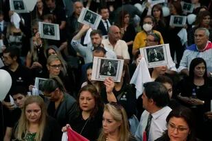 Personas sosteniendo una imagen del difunto fiscal antidrogas Marcelo Pecci asisten a una reunión para exigir justicia por su asesinato, en Asunción, Paraguay, el viernes 13 de mayo de 2022. (AP Foto/Jorge Saenz)