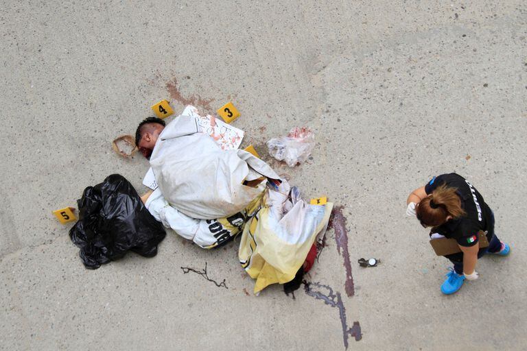 Técnicos forenses junto a los restos de un hombre que había sido desmembrado y dejado en bolsas de plástico en la escena del crimen en Acapulco,