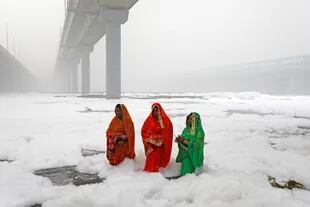 Tres mujeres se bañan en el contaminado río de la ciudad 