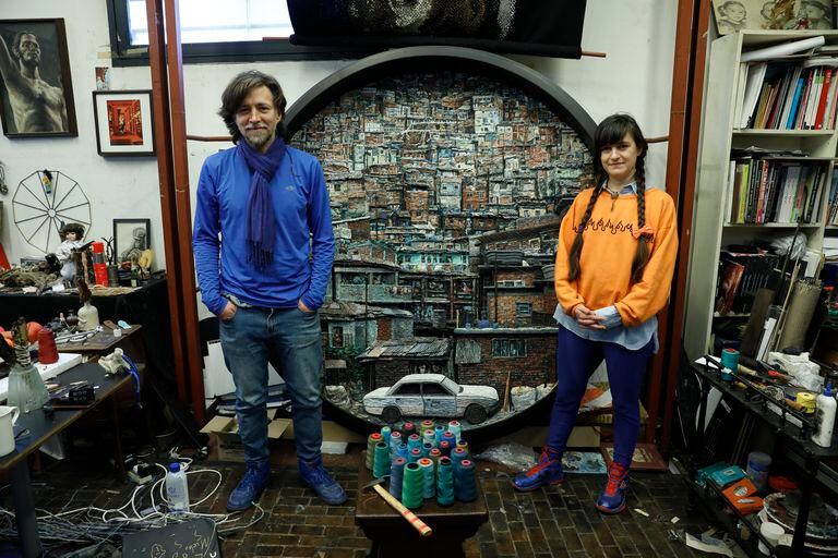 Manuel Mendanha y Juliana Laffitte, las dos partes de Mondongo, en su taller, frente a un tondo creado con imágenes de villas de emergencia de distintas partes del mundo