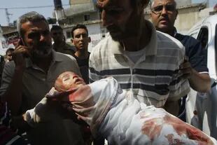 Un padre carga a su hijo herido para llevarlo a un puesto sanitario en medio de un bombardeo israelí en Gaza