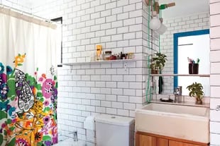 Explosión de color para esta cortina de baño de Urban Outfitters. El resto, todo blanco: cerámicas esmaltadas, estantes y una bacha de demolición. 