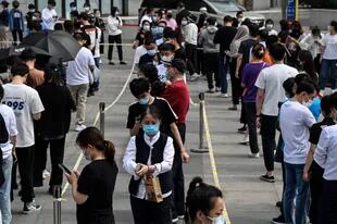 La gente hace cola para someterse a la prueba del coronavirus en un centro de pruebas improvisado frente a edificios de oficinas en Pekín el 25 de abril de 2022. 