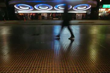 La sombra de un peatón se funde en las luces del ingreso al teatro Opera, uno de los más tradicionales de la calle Corrientes