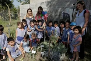 Las maestras jardineras reparten entre los chicos los alimentos que producen en la huerta.