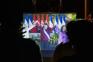 Los vecinos ven la toma de posesión del presidente Daniel Ortega, en una pantalla gigante en un parque en el barrio Julio Buitrago de Managua, Nicaragua, el lunes 10 de enero de 2022. (AP Foto/Andres Nunez)