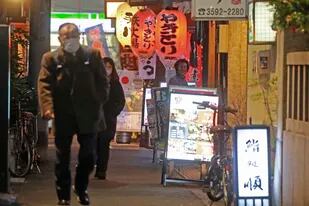 Personas con mascarillas para protegerse del COVID-19 caminan por una calle llena de bares y restaurantes, el 19 de enero de 2022, en Tokio. (AP Foto/Koji Sasahara, archivo)
