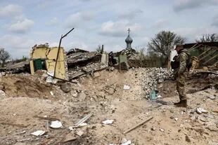 Un militar ucraniano mira dentro de un cráter producto de un bombardeo en el pueblo de Yatskivka, en el este de Ucrania, el 16 de abril de 2022. 