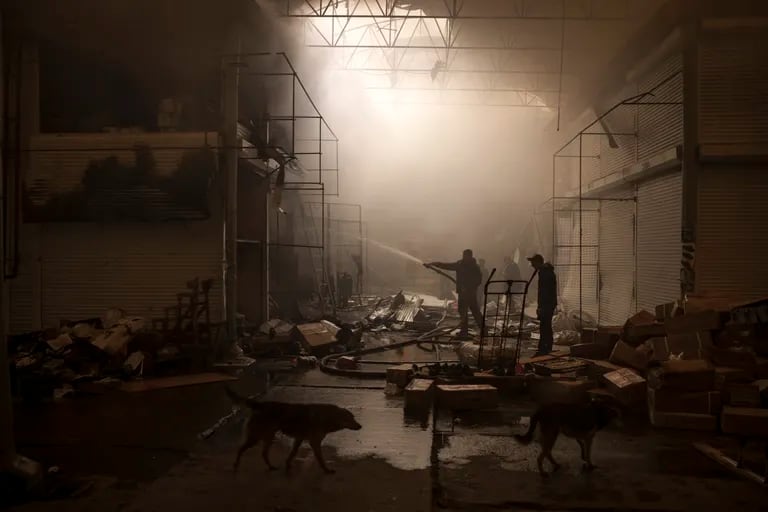 La gente intenta extinguir un incendio en un mercado después del ataque ruso, en Kharkiv, Ucrania, el 25 de marzo de 2022. (AP Photo/Felipe Dana)