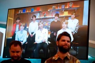 El artista danés Jakob Kudsk Steenson (R) se sienta frente a un monitor de transmisión en vivo de la banda BTS durante el anuncio de su nuevo trabajo Catharsis en el lanzamiento del proyecto de arte público global "Connect, BTS", en Serpentine Galería en Londres, el 14 de enero