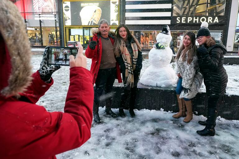 Un grupo de personas posa junto a un muñeco de nieve en Times Square, en el corazón de Manhattan