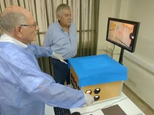 Carlos Spector, decano de la Facultad de Ciencias de la Salud, y Alfredo André, prosecretario de la UCES (centro), operan el simulador que diseñaron durante la pandemia de Covid-19