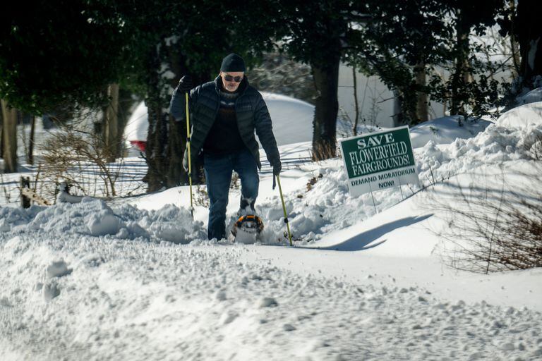 A man walks in snowshoes after a snowstorm hit the Northeast on January 30, 2022 in Centereach, New York.  A powerful northeasterly storm brought blinding blizzard conditions with high winds that caused some power outages along the Mid-Atlantic and New England coast.
