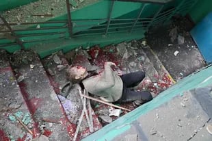 El cuerpo de una mujer yace en una escalera de una escuela en Kharkiv, parcialmente destruida por un cohete el 2 de junio de 2022.