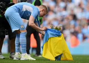 Pemain sepak bola Ukraina Oleksandr Zinchenko dari Manchester City membungkus trofi dengan bendera negaranya