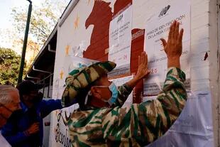 Un miembro de la milicia estatal coloca un cartel informativo durante las elecciones regionales de Venezuela