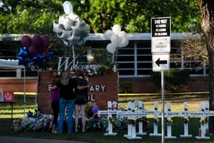 Una familia rinde homenaje frente a las cruces que llevan los nombres de las víctimas en la escuela primaria Robb en Uvalde, Texas, jueves 26 de mayo de 2022. (AP Foto/Jae C. Hong)
