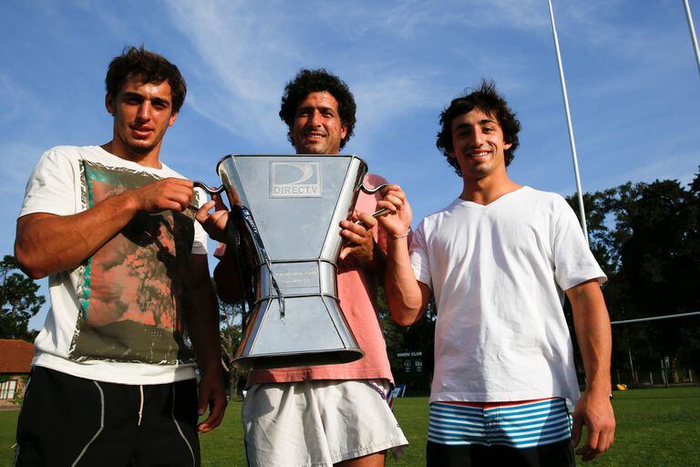 La copa de la URBA en 2014, uno de los muchos años en que el dominante Hindú resultó campeón de Buenos Aires; Senillosa la sostiene flanqueado por Bautista Ezcurra y Bautista Álvarez. El exback levantó 17 trofeos, una cifra que parece inalcanzable.