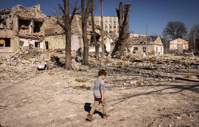   A boy walks in front of a damaged school in the northern Ukrainian city of Zhytomyr on March 23, 2022.