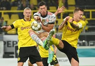 Lewandowski y Reus disputan la pelota en la intensa final que Bayern Munich le ganó a Borussia Dortmund; atrás, Haaland