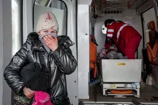 Una mujer llora mientras los paramédicos intentan hacer reaccionar a una chica herida en un ataque ruso en Mariupol