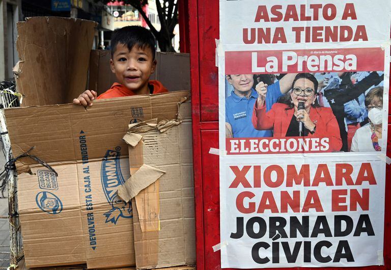Un chico juega al lado de un kiosco de revistas donde se anuncia el triunfo de Xiomara Castro
