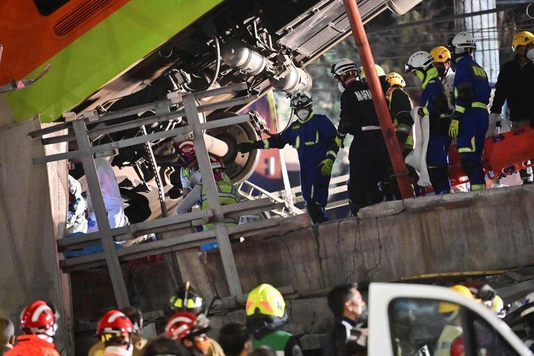 Rescatistas y bomberos trabajan para sacar a los pasajeros del interior del tren que quedó colgado de la estructura del puente, entre fierros retorcidos y cables.