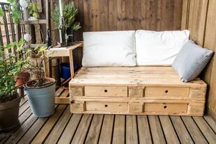 Simple y barato: pallets de madera, macetas con plantas y unos almohadones en colores claros y gris